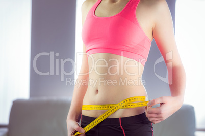 Slim woman measuring waist with tape measure