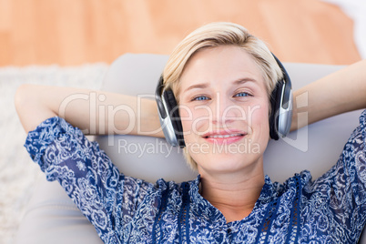 Pretty blonde woman listening music on the couch