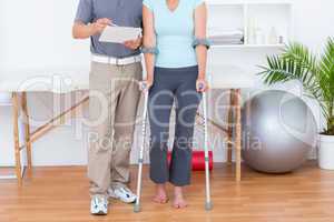 Woman using crutch and talking with her doctor