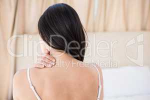 Pretty brunette with neck pain on bed