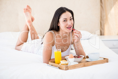 Pretty brunette eating her breakfast on bed