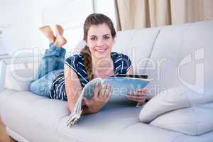 Happy woman reading a magazine on couch