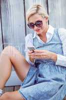 Pretty blonde woman wearing sun glasses and texting with her mob