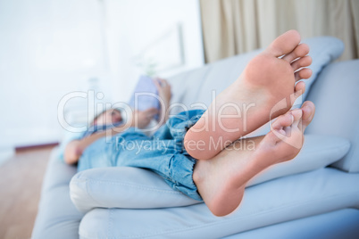 Peaceful woman lying on couch reading a book