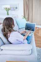 Pretty brunette using her laptop on couch