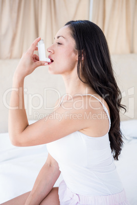 Pretty brunette using inhaler on bed Pretty brunette using inhaler on bed