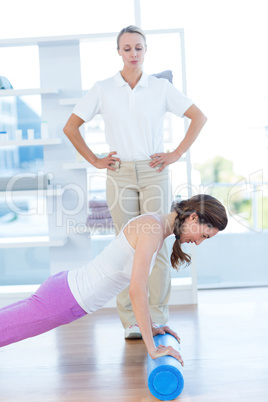 Trainer working with woman on exercise mat