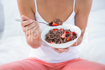 Attractive woman eating cereal in her bed