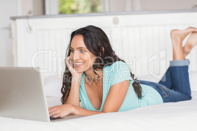 Happy brunette using her laptop