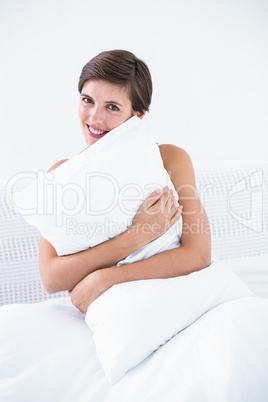 Happy brunette hugging her pillow