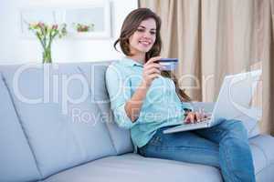 Pretty brunette doing online shopping with her laptop