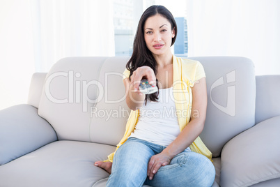 Pretty brunette holding remote control on couch