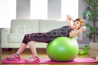 Fit woman doing sit ups on exercise ball