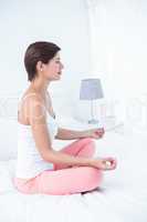Peaceful woman doing yoga in her bed
