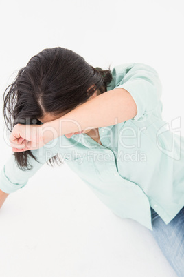 Sad woman sitting on the floor and hiding her face