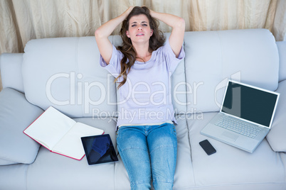 Stressed brunette holding her head on couch