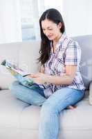 Pretty brunette reading a magazine on couch