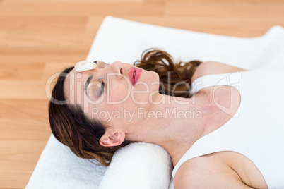 Relaxed brunette lying on mat with stones