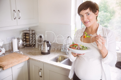 Pregnant woman having bowl of salad