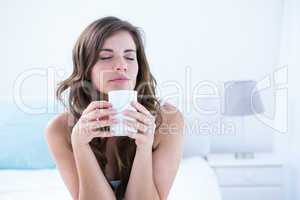 Peaceful brunette drinking a cup of coffee
