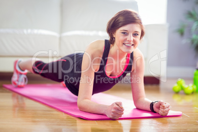 Fit woman doing plank on mat