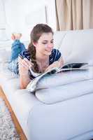Peaceful woman reading a magazine on couch
