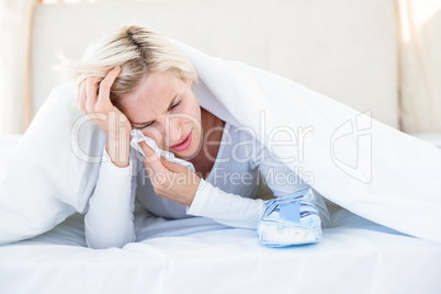 Sad blonde woman lying on the bed