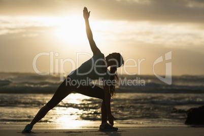 Sporty brunette stretching on the beach