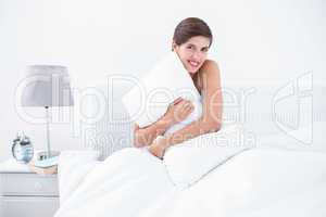 Happy brunette hugging her pillow