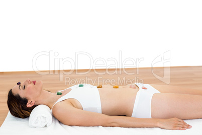 Relaxed brunette lying on mat with stones