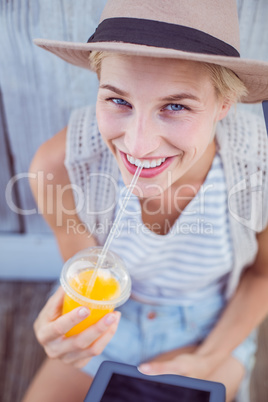 Pretty blonde woman using her tablet and holding orange juice