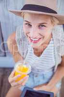 Pretty blonde woman using her tablet and holding orange juice