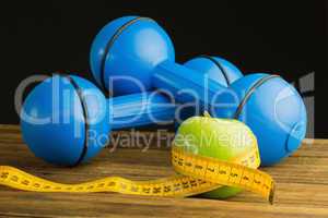 Blue dumbbells with green apple and measuring tape