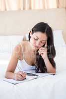 Pretty brunette writing on bed