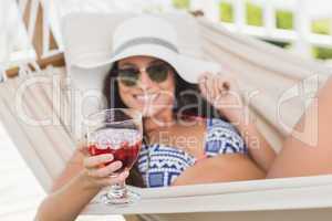 Pretty brunette relaxing on a hammock and drinking cocktail