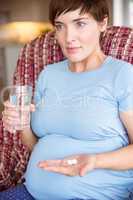 Pregnant woman taking a vitamin tablet