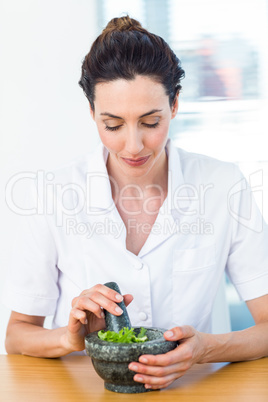 Scientist mixing herbs with pestle and mortar