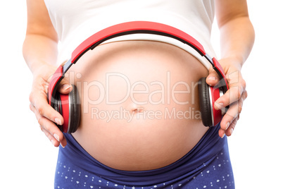 Pregnant woman holding earphones over bump