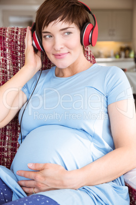 Pregnant woman putting headphones over bump