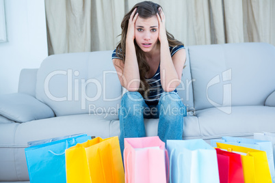 Regretful woman looking at many shopping bags