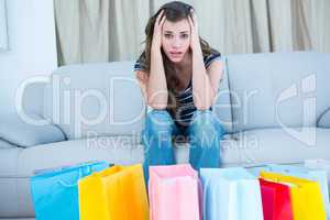 Regretful woman looking at many shopping bags