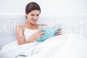 Pretty woman reading a book in her bed