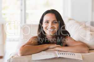 Pretty brunette reading magazine on the couch