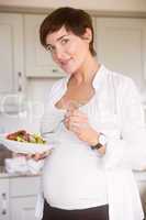 Pregnant woman having bowl of salad