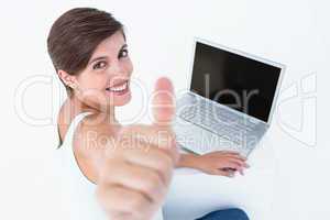 Attractive woman using laptop with thumb up