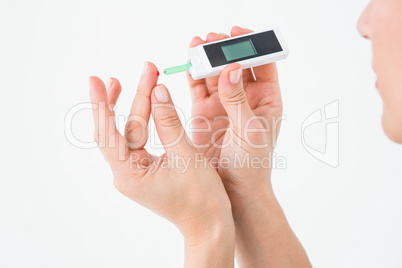 Diabetic woman using blood glucose monitor