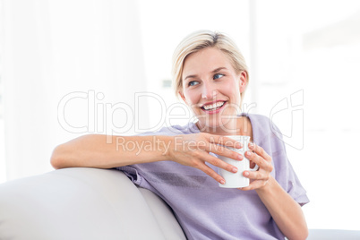 Pretty blonde woman relaxing on the couch and holding a mug