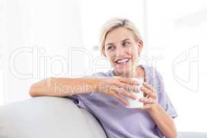 Pretty blonde woman relaxing on the couch and holding a mug