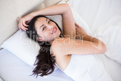 Pretty brunette smiling on bed