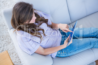 Pretty brunette using her tablet pc on couch